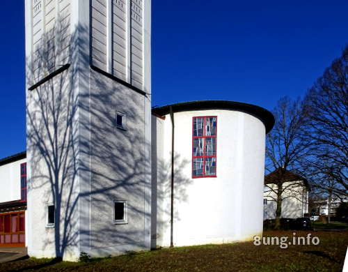 Baumschatten auf weißem Kirchturm vor blauem Winterhimmel