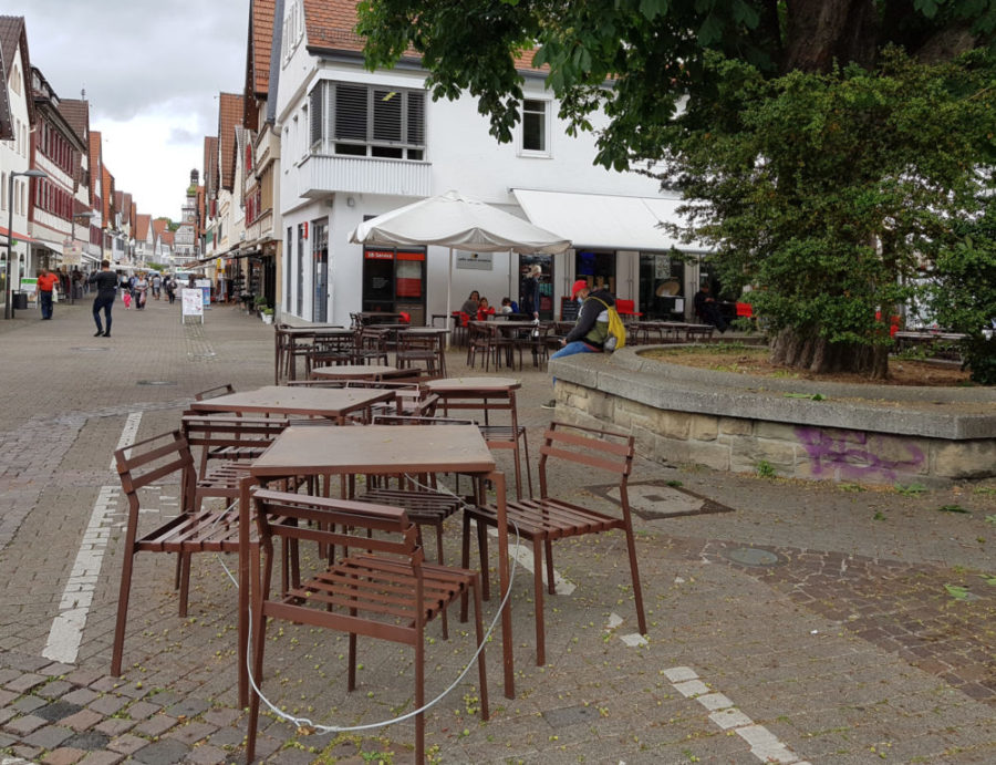 leere Tische und Stühle im Strassencafe, graue Wolken