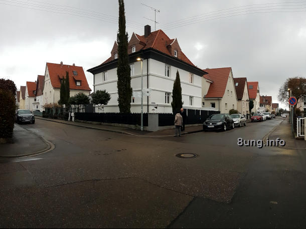 Straßenkreuzung mit grauen Wolken, weißes Haus, Passanten